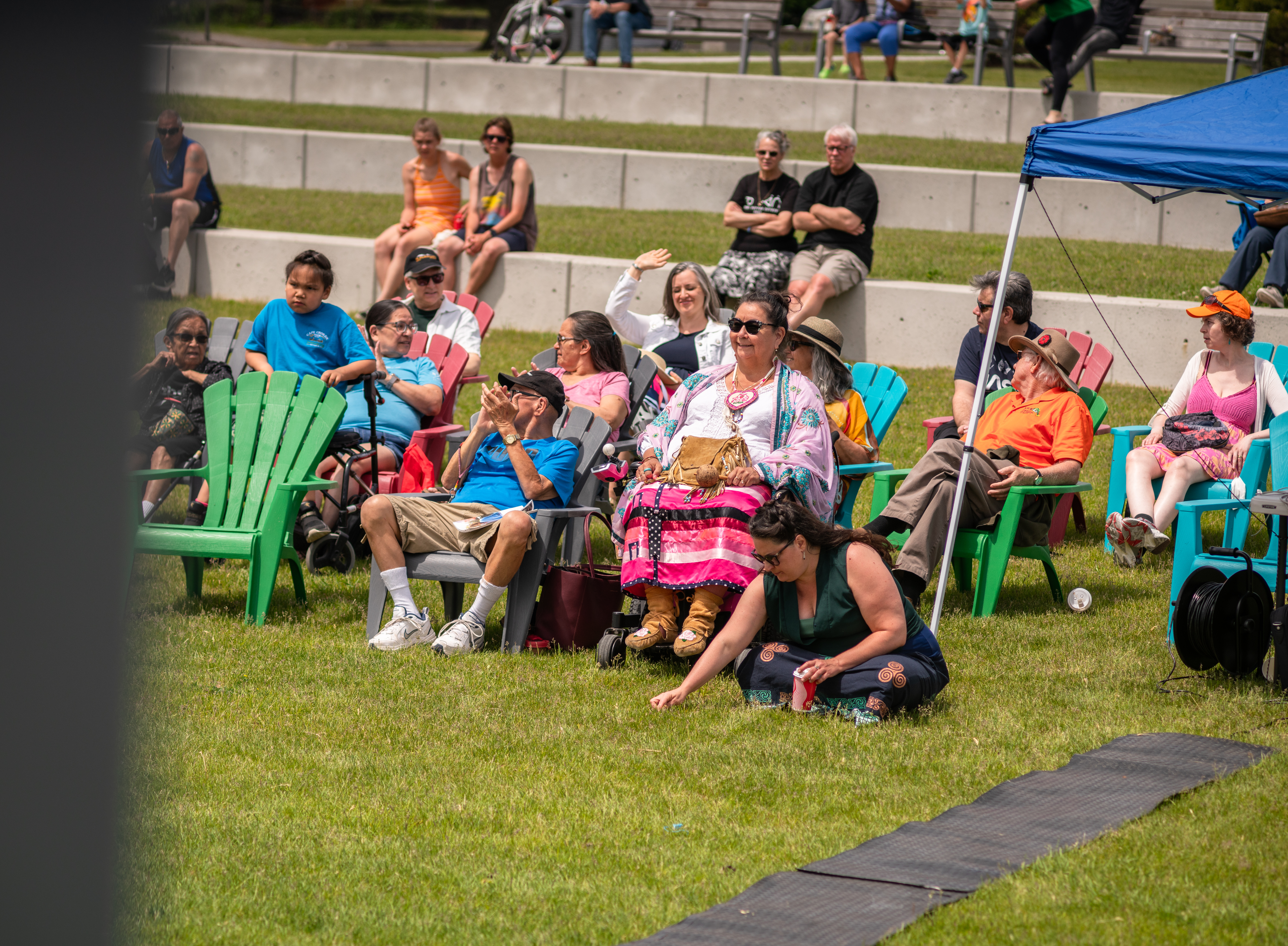 A crowd of people is sitting on chairs in the amphitheatre watching an event.