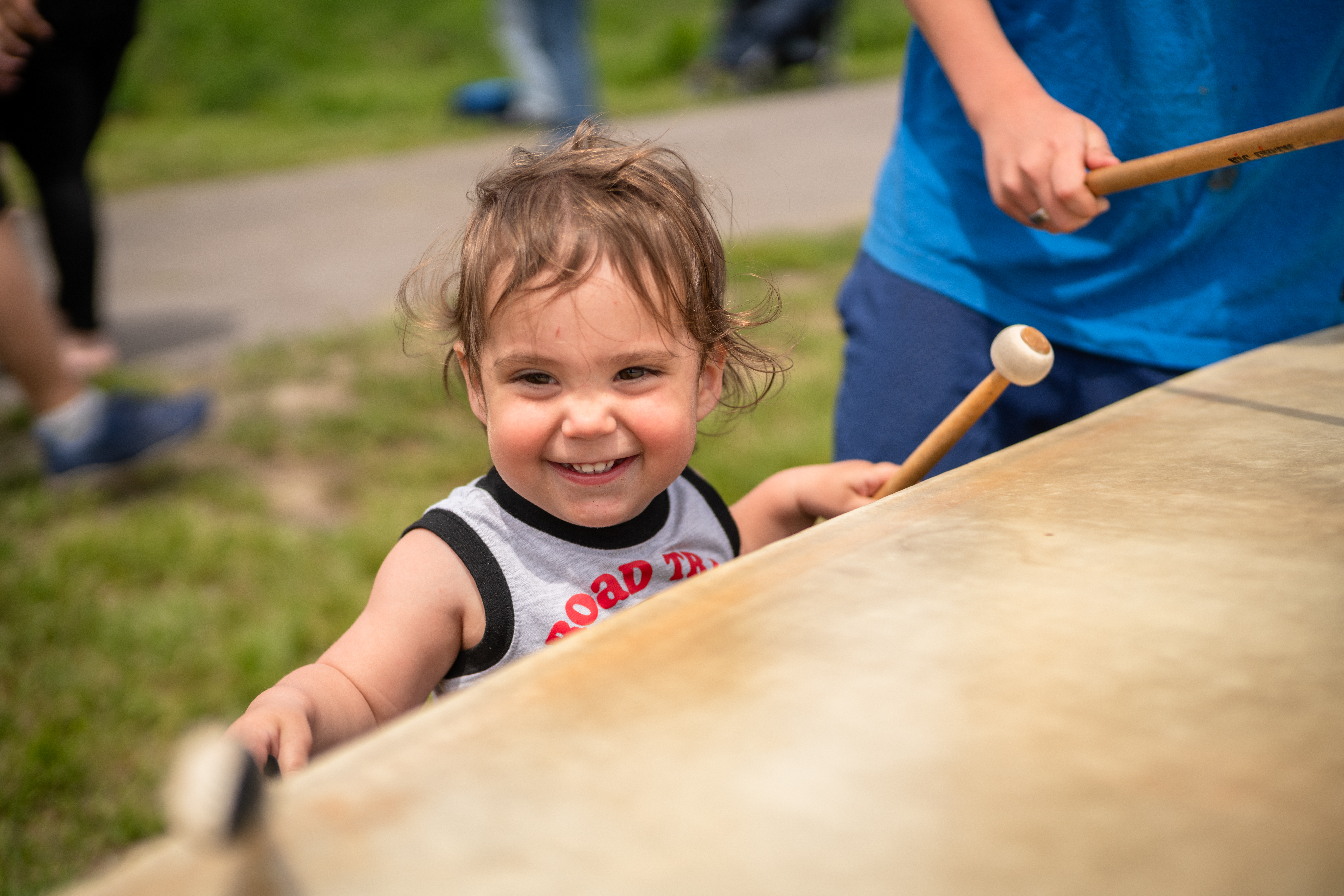 A child smiling while holding percussion instruments.