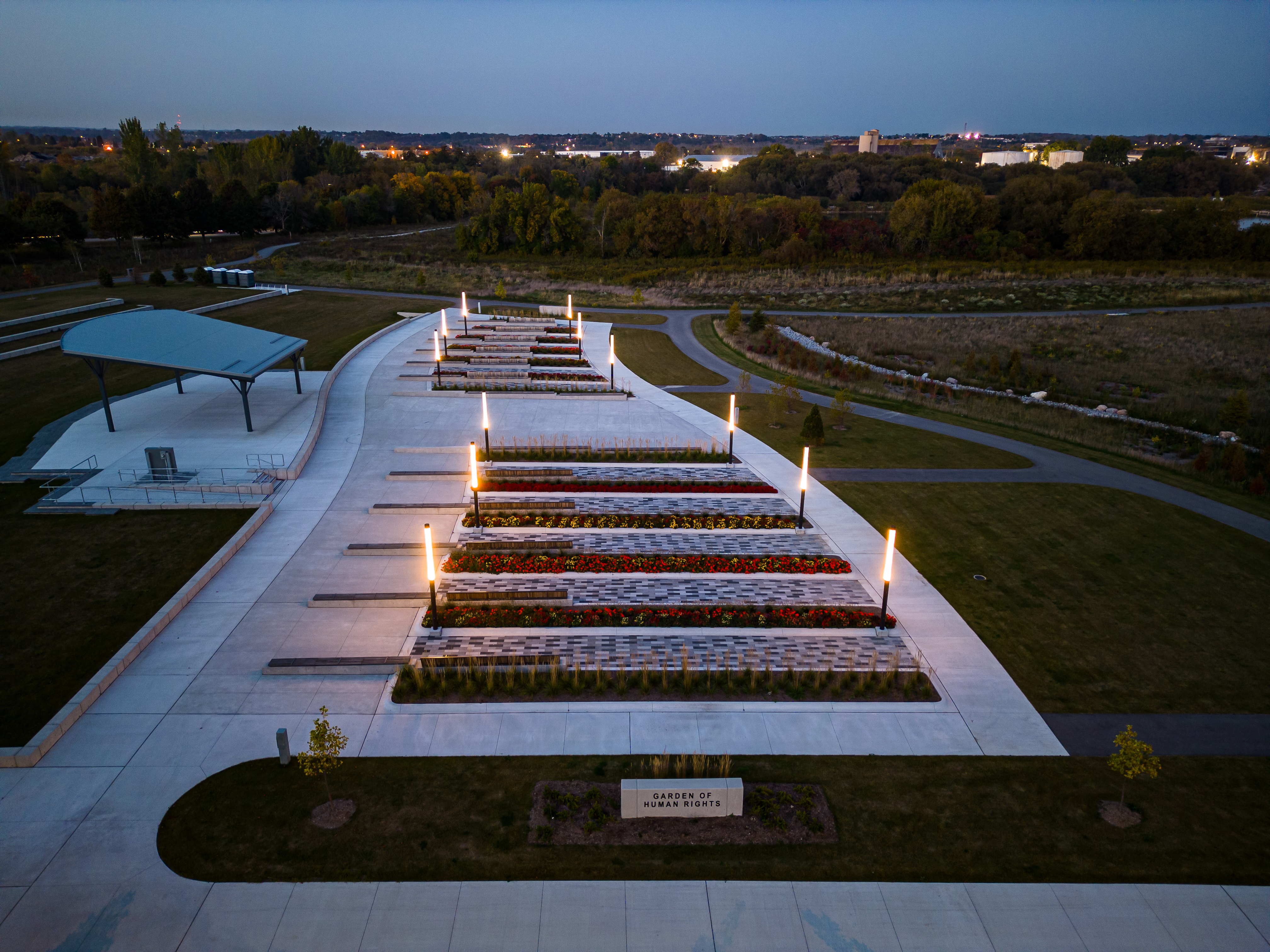 An aerial shot of the Garden of Human Rights in the evening, with several lights illuminating each of the garden beds.