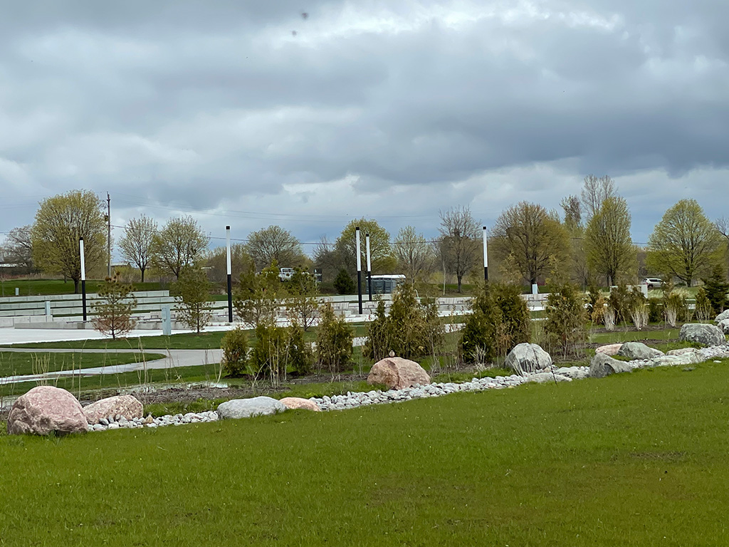 A strip of stones of varying sizes surrounding a collection of trees in front of the Garden of Human Rights.